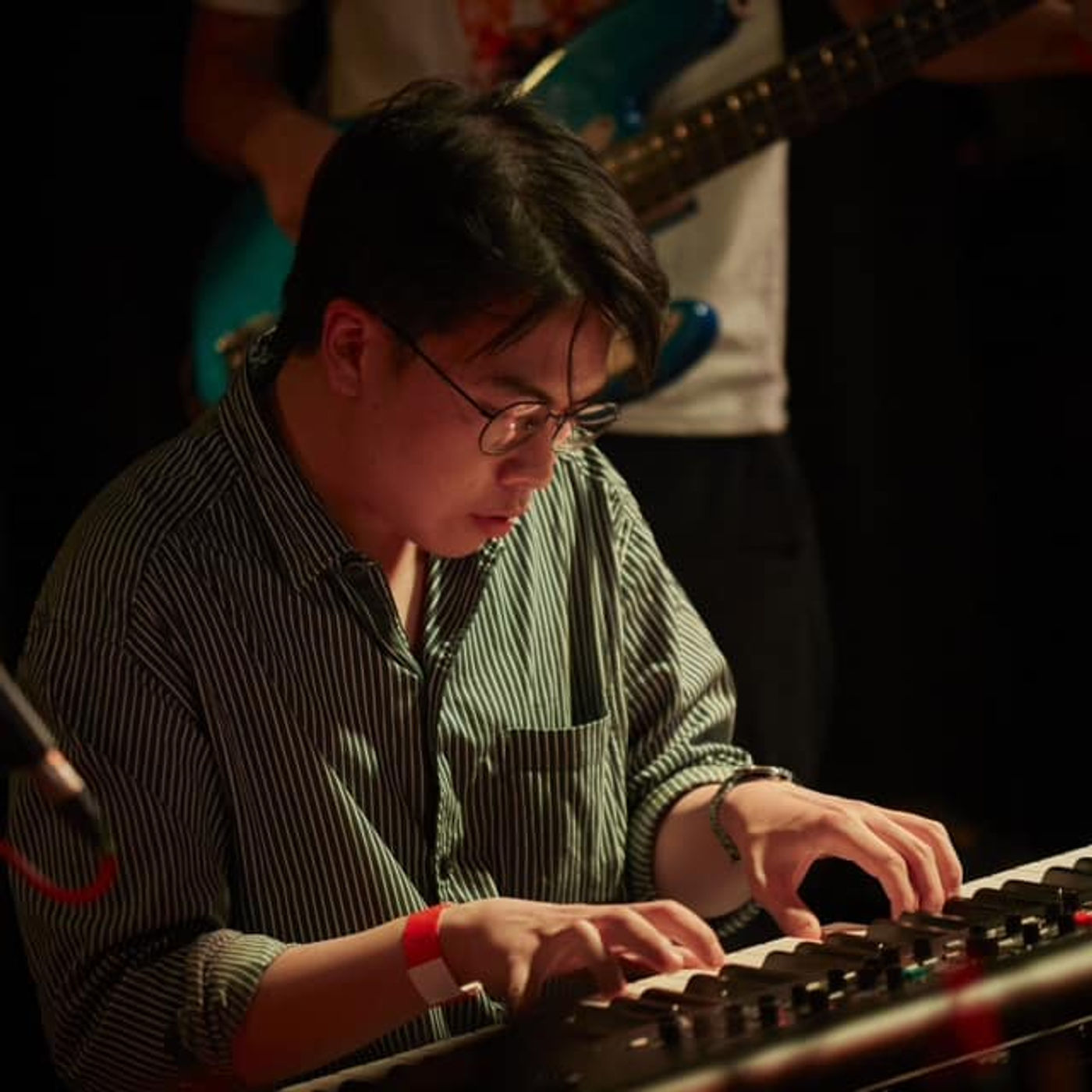 Tanakrit performing a piano solo under warm stage lights at a live concert