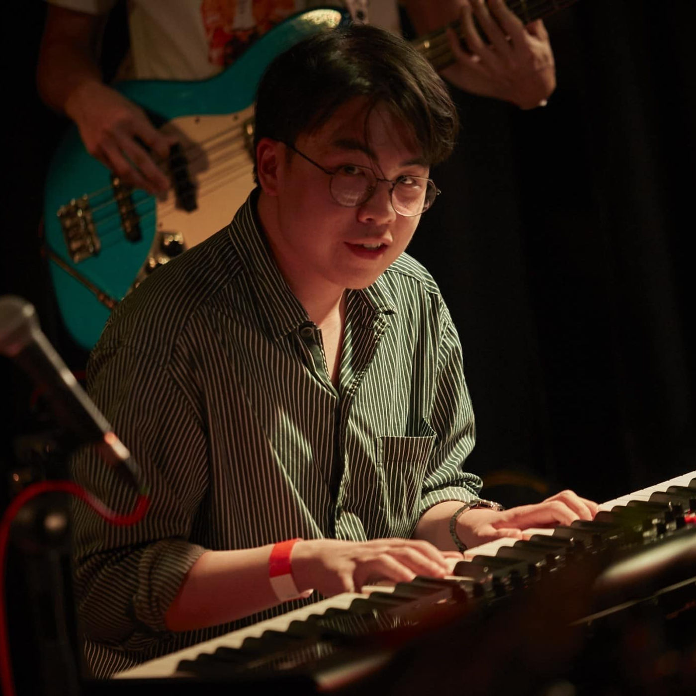 Tanakrit recording in a studio session, captured mid-phrase at the piano